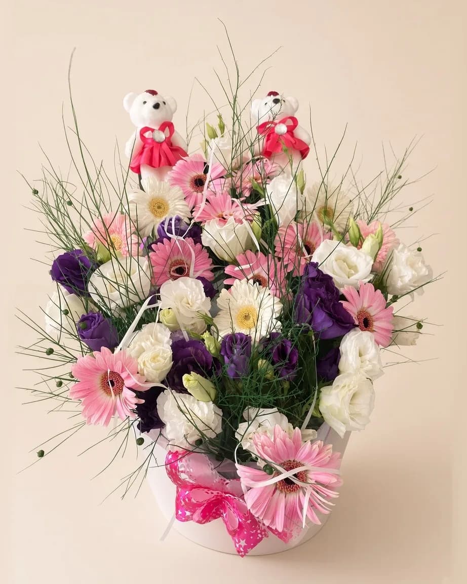 Beyaz kutuda pembe ve beyaz gerberalar, mor lisianthus ve iki peluş ayıcıktan aranjman