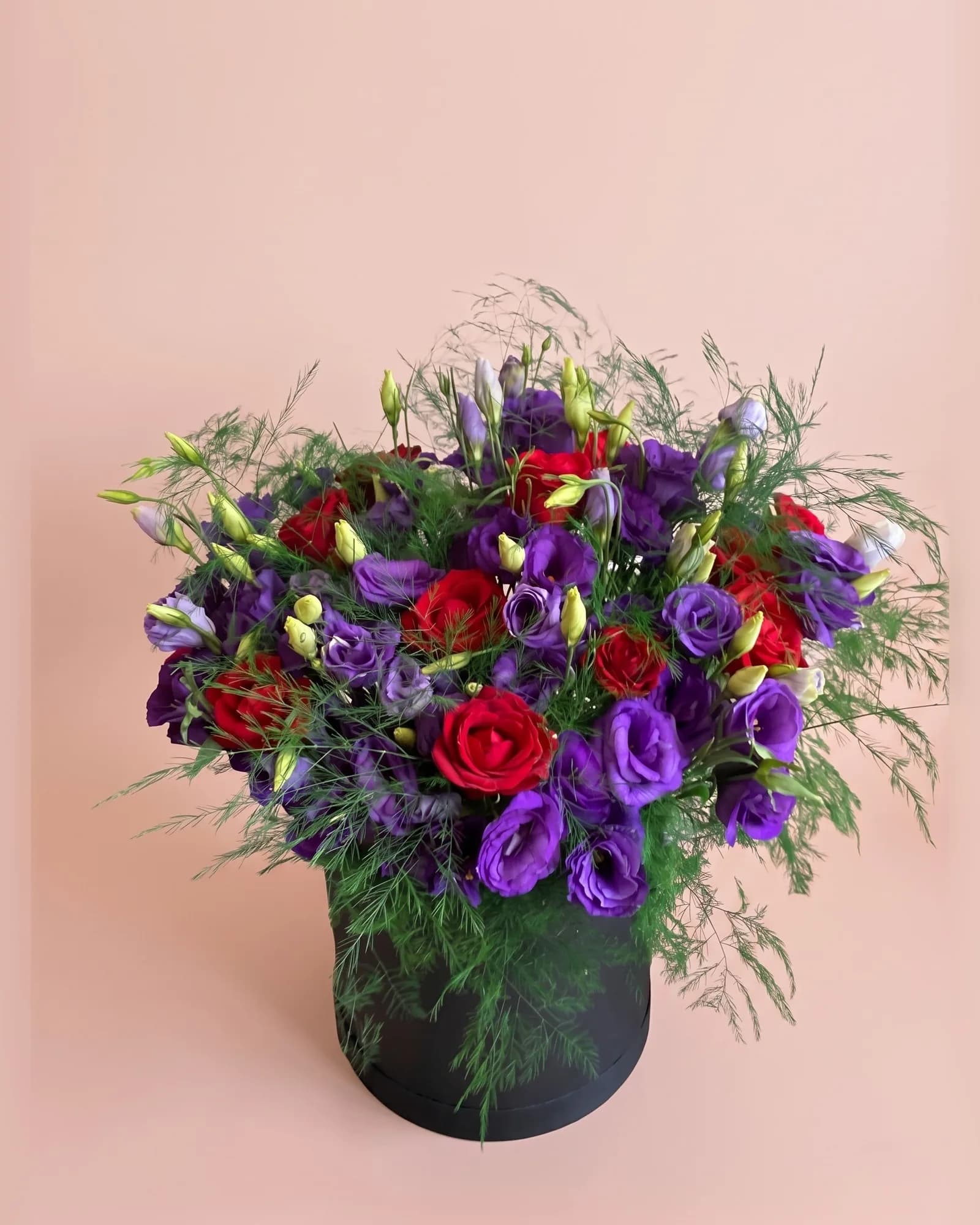 Siyah silindir kutuda mor lisianthus ve kırmızı güllerden aranjman